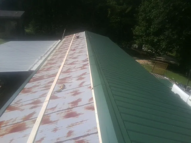 Old rusted panels beside newly installed green metal roofing — Wind Damage Roof Repair by Roofing Brothers in East Fultonham