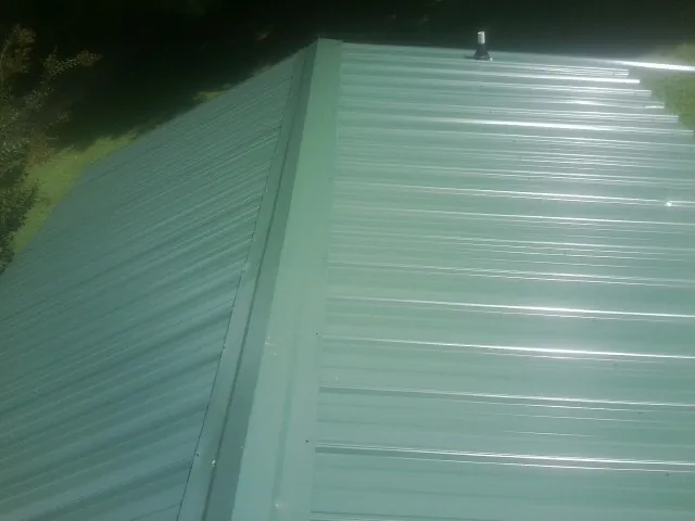 New green metal panels meeting at the ridge of a roof — Flat Roof Repair work by our crew in East Fultonham