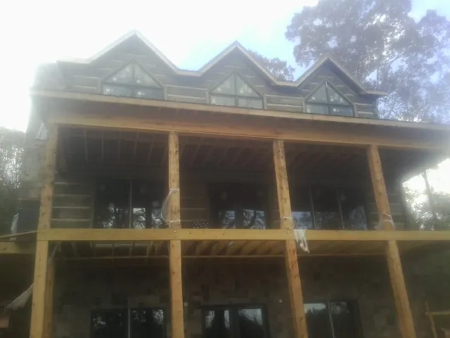 Dormers and porch framing on a large log home under construction — Roof Coating work by our crew in East Fultonham