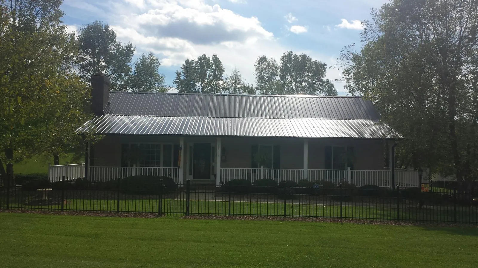 Gray metal roof on a brick ranch with a full width front porch — Gutter Guard Installation work by our crew in East Fultonham