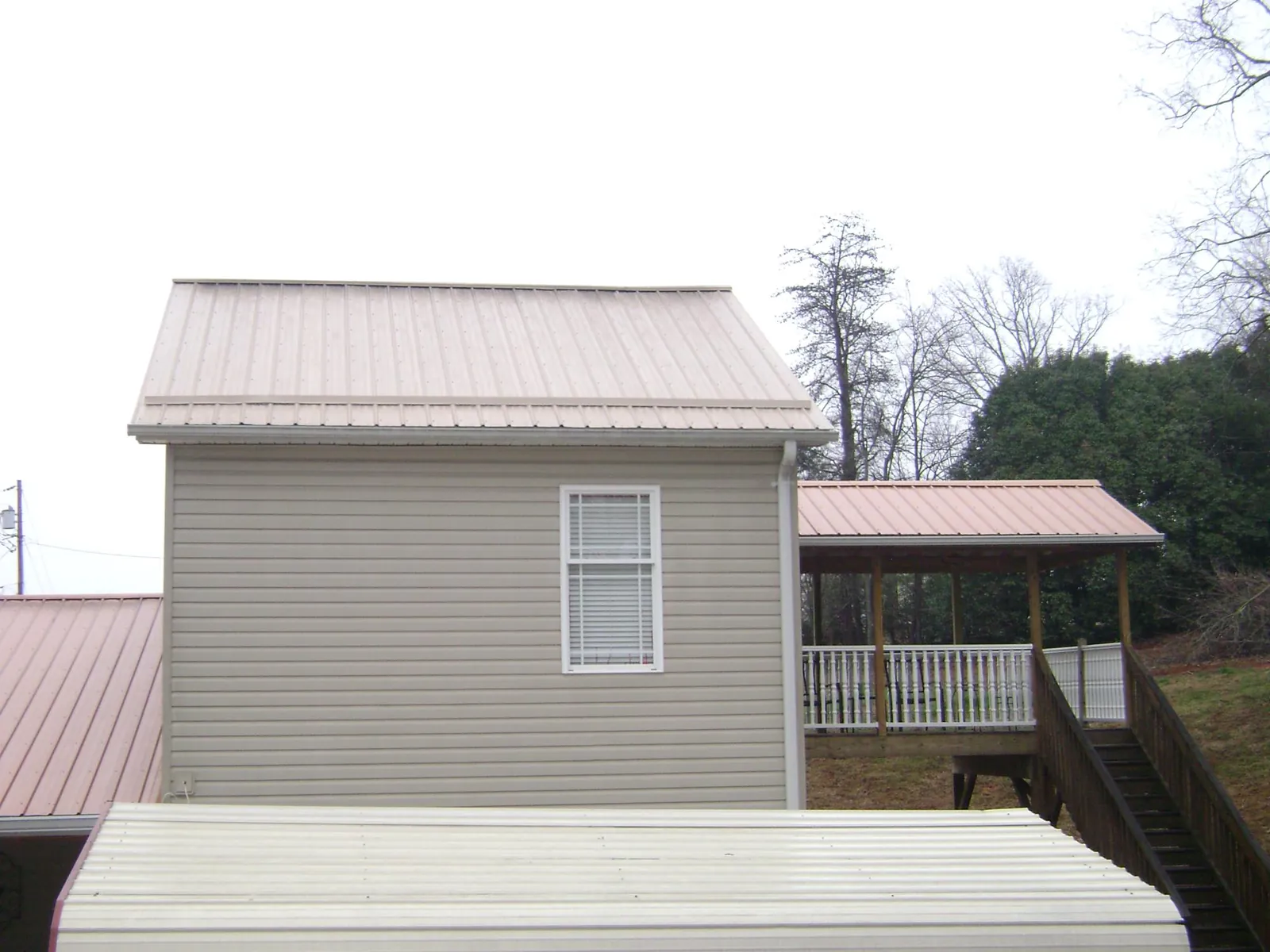 Tan metal roofs on a two story addition and attached porch, from a Roof Replacement job in East Fultonham