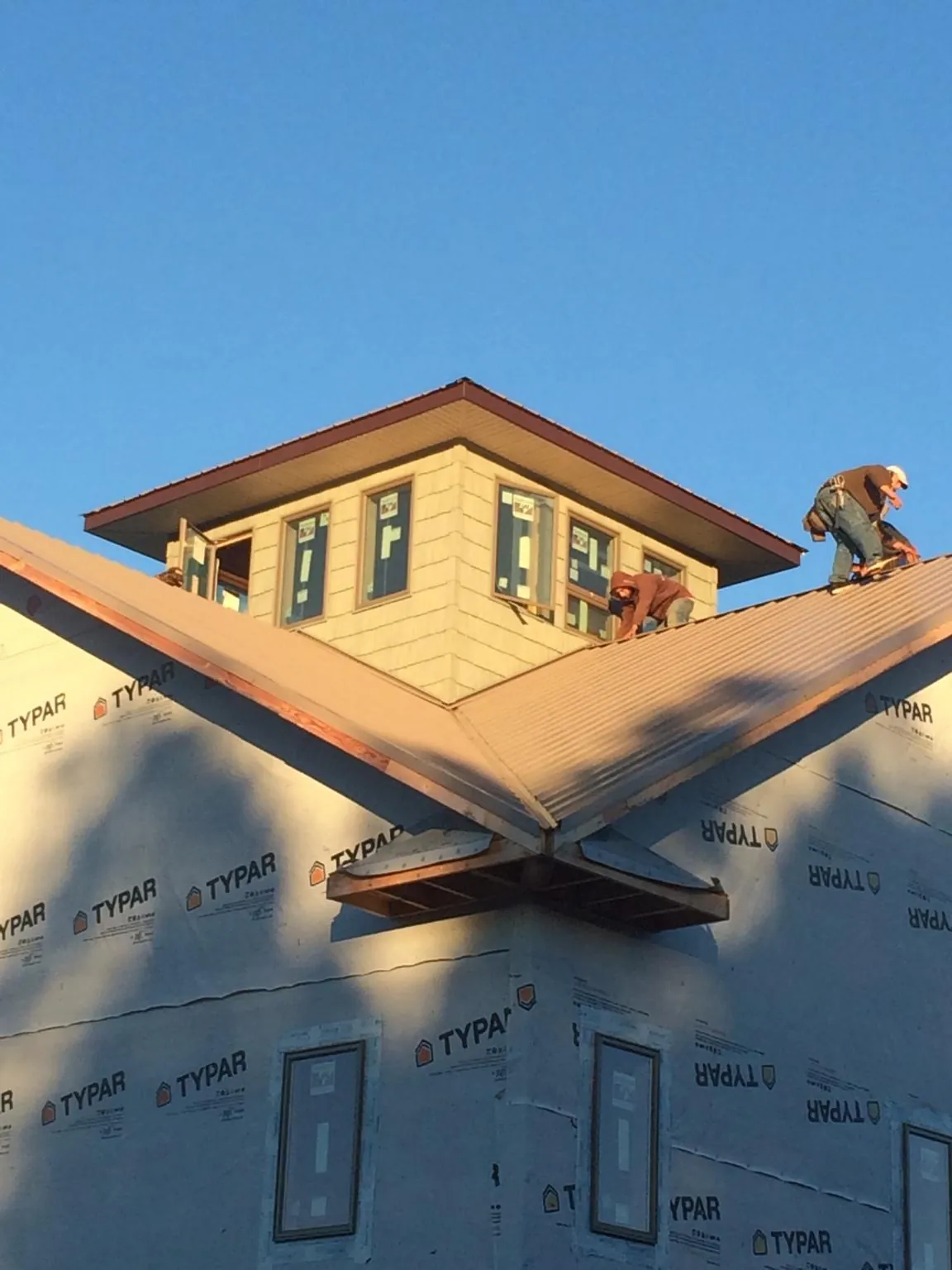 Roofers working around a rooftop cupola on a new metal roof at sunset — Roof Waterproofing in East Fultonham by Roofing Brothers